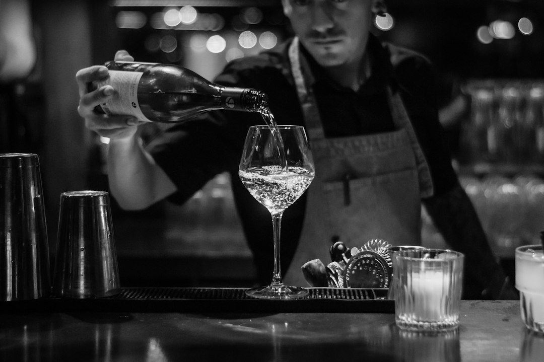 Bartender schenkt drank in een wijnglas achter de bar